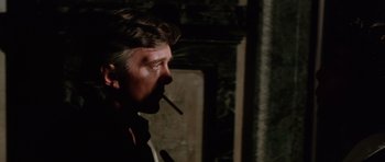 Movie still from “Deep Red” (1975), directed by Dario Argento – A man smoking a cigarette in a dark room; Close Up shot, Over the shoulder angle