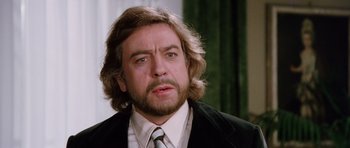 Movie still from “Deep Red” (1975), directed by Dario Argento – A person wearing a suit and tie; Close Up shot, Low angle