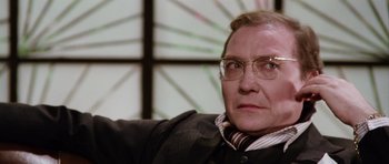 Movie still from “Deep Red” (1975), directed by Dario Argento – An older man wearing glasses and a suit; Close Up shot, Over the shoulder angle