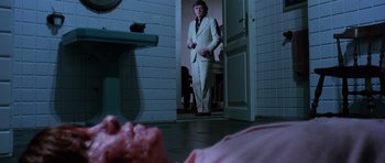 Movie still from “Deep Red” (1975), directed by Dario Argento – A man in a white suit standing in front of a sink; Wide shot, Low angle