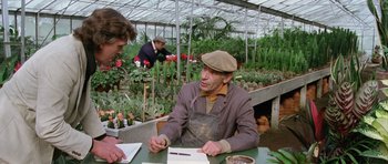 Movie still from “Deep Red” (1975), directed by Dario Argento – A man sitting at a table in front of plants; Medium shot, High angle
