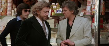 Movie still from “Deep Red” (1975), directed by Dario Argento – Two men talking to each other while standing next to each other; Medium shot, Over the shoulder angle
