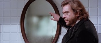 Movie still from “Deep Red” (1975), directed by Dario Argento – A man standing in front of a round mirror; Close Up shot, Over the shoulder angle