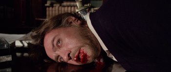 Movie still from “Deep Red” (1975), directed by Dario Argento – A man with a knife in his mouth; Close Up shot, High angle