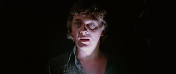 Movie still from “Deep Red” (1975), directed by Dario Argento – A man in a black shirt is looking at the camera; Close Up shot, Low angle