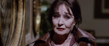 Movie still from “Deep Red” (1975), directed by Dario Argento – An older woman wearing a leather jacket and pearls; Close Up shot, High angle