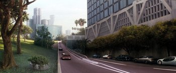 Movie still from “Demolition Man” (1993), directed by Marco Brambilla – Cars driving down a street next to a tall building; Extreme Wide shot, High angle