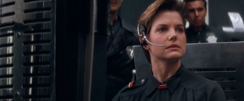 Movie still from “Demolition Man” (1993), directed by Marco Brambilla – A woman with a headset on looking at something; Close Up shot, Over the shoulder angle