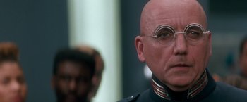 Movie still from “Demolition Man” (1993), directed by Marco Brambilla – A bald man with glasses is looking at the camera; Close Up shot, Low angle