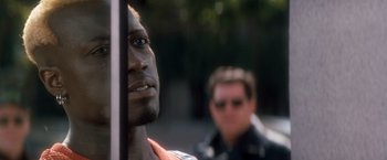 Movie still from “Demolition Man” (1993), directed by Marco Brambilla – A man's face with another man in the background; Close Up shot, Over the shoulder angle
