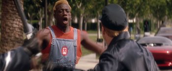 Movie still from “Demolition Man” (1993), directed by Marco Brambilla – A man in a red shirt is yelling at another man; Medium shot, Over the shoulder angle