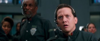 Movie still from “Demolition Man” (1993), directed by Marco Brambilla – A man in a police uniform with headphones on; Close Up shot, Low angle