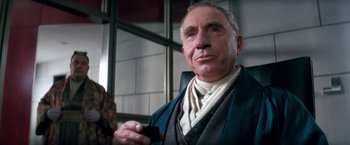 Movie still from “Demolition Man” (1993), directed by Marco Brambilla – An older man holding a cell phone in his hand; Close Up shot, Low angle