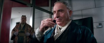 Movie still from “Demolition Man” (1993), directed by Marco Brambilla – An older man holding a cell phone up to his ear; Close Up shot, Low angle