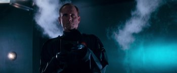 Movie still from “Demolition Man” (1993), directed by Marco Brambilla – A man holding a camera in a dark room; Close Up shot, Low angle