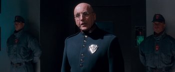 Movie still from “Demolition Man” (1993), directed by Marco Brambilla – An older man in a military uniform with glasses; Close Up shot, Low angle