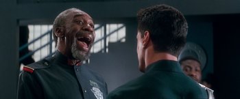 Movie still from “Demolition Man” (1993), directed by Marco Brambilla – Two men talking to each other in front of each other; Close Up shot, Low angle