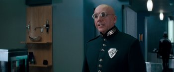 Movie still from “Demolition Man” (1993), directed by Marco Brambilla – A bald man in a uniform with glasses; Close Up shot, Low angle