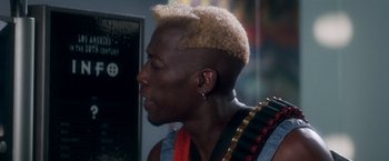Movie still from “Demolition Man” (1993), directed by Marco Brambilla – A person with a mohawk haircut; Close Up shot, Over the shoulder angle