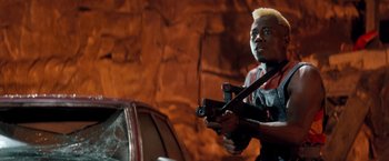 Movie still from “Demolition Man” (1993), directed by Marco Brambilla – A man holding a gun while standing in front of a car; Close Up shot, Low angle