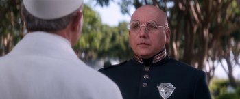 Movie still from “Demolition Man” (1993), directed by Marco Brambilla – A man in a uniform and glasses talking to another man; Close Up shot, Over the shoulder angle