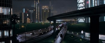 Movie still from “Demolition Man” (1993), directed by Marco Brambilla – A city street at night with cars driving on it; Extreme Wide shot, High angle