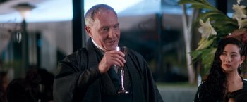 Movie still from “Demolition Man” (1993), directed by Marco Brambilla – An older man holding a glass of wine; Close Up shot, Over the shoulder angle