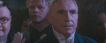 Movie still from “Demolition Man” (1993), directed by Marco Brambilla – A man in a suit and tie standing next to another man in a suit and tie; Close Up shot, Over the shoulder angle