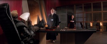 Movie still from “Demolition Man” (1993), directed by Marco Brambilla – A man and a woman standing next to a table; Wide shot, High angle