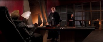 Movie still from “Demolition Man” (1993), directed by Marco Brambilla – A man and a woman are standing at a table; Wide shot, Over the shoulder angle