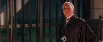 Movie still from “Demolition Man” (1993), directed by Marco Brambilla – An older man wearing a suit and tie; Medium shot, Low angle