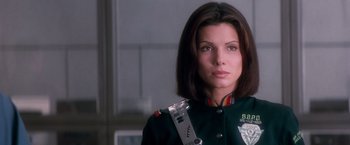 Movie still from “Demolition Man” (1993), directed by Marco Brambilla – A woman in a uniform with a gun in her hand; Close Up shot, Low angle