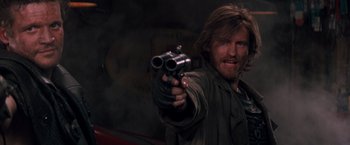 Movie still from “Demolition Man” (1993), directed by Marco Brambilla – A man holding a gun in his right hand; Close Up shot, Low angle