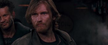 Movie still from “Demolition Man” (1993), directed by Marco Brambilla – A person with long hair and a beard; Close Up shot, Over the shoulder angle