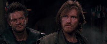 Movie still from “Demolition Man” (1993), directed by Marco Brambilla – A person with long hair and a beard; Close Up shot, Over the shoulder angle