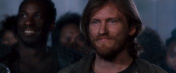 Movie still from “Demolition Man” (1993), directed by Marco Brambilla – A person with long hair and a beard; Close Up shot, Over the shoulder angle