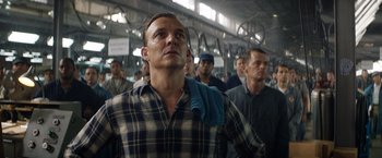 Movie still from “Ford v Ferrari” (2019), directed by James Mangold – A group of men standing in a room with bicycles; Medium shot, Low angle