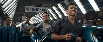 Movie still from “Ford v Ferrari” (2019), directed by James Mangold – A group of young men sitting next to each other; Medium shot, Low angle