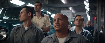 Movie still from “Ford v Ferrari” (2019), directed by James Mangold – A group of men standing next to each other in a building; Medium shot, Low angle