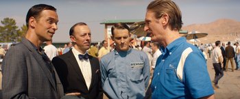 Movie still from “Ford v Ferrari” (2019), directed by James Mangold – A group of men standing next to each other on a field; Medium shot, Over the shoulder angle