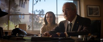 Movie still from “Ford v Ferrari” (2019), directed by James Mangold – An older man and a younger woman sitting at a table; Medium shot, Low angle