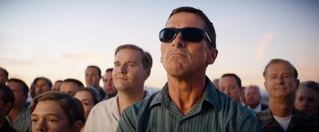 Movie still from “Ford v Ferrari” (2019), directed by James Mangold – A man with sunglasses is standing next to another man; Close Up shot, Low angle