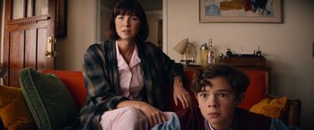 Movie still from “Ford v Ferrari” (2019), directed by James Mangold – A woman sitting next to a young boy in a room; Medium shot, Low angle