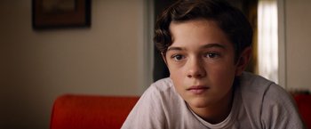 Movie still from “Ford v Ferrari” (2019), directed by James Mangold – A young boy is sitting on a couch; Close Up shot, High angle