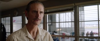 Movie still from “Ford v Ferrari” (2019), directed by James Mangold – A person wearing a white shirt near a window; Close Up shot, Over the shoulder angle