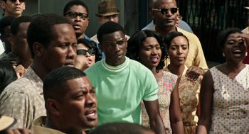 Movie still from “Detroit” (2017), directed by Kathryn Bigelow – A group of people standing around each other in front of a building; Medium shot, High angle