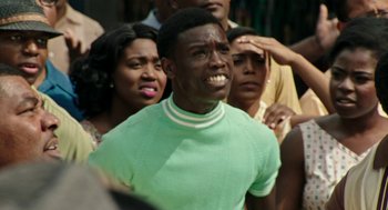 Movie still from “Detroit” (2017), directed by Kathryn Bigelow – A group of people standing around a man in a green shirt; Close Up shot, Over the shoulder angle