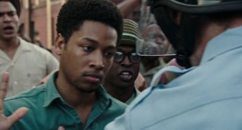 Movie still from “Detroit” (2017), directed by Kathryn Bigelow – A group of men standing next to each other in front of a police officer; Close Up shot, Over the shoulder angle