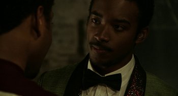 Movie still from “Detroit” (2017), directed by Kathryn Bigelow – A person wearing a suit and a bow tie; Close Up shot, Over the shoulder angle
