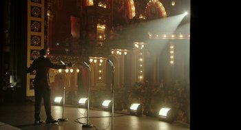 Movie still from “Detroit” (2017), directed by Kathryn Bigelow – A group of microphones on a stage in front of an audience; Extreme Wide shot, High angle